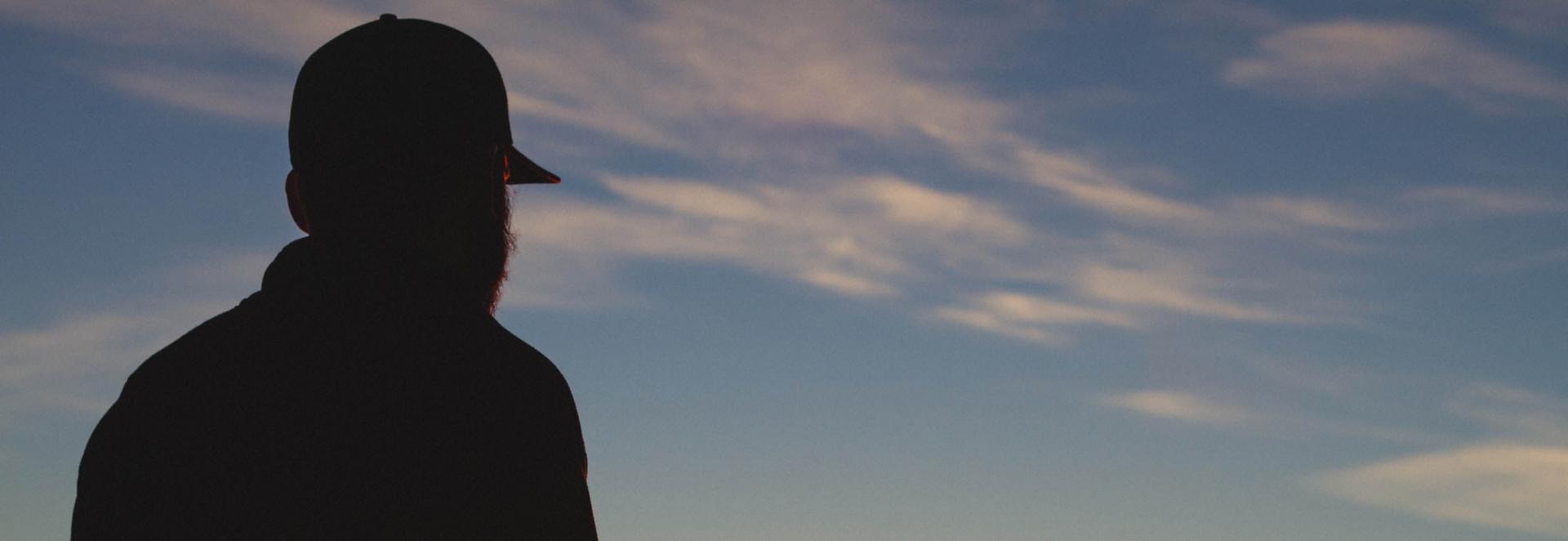 Silhouette of person in baseball cap